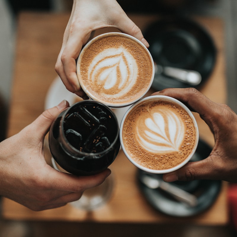 Cups of fresh latte art shared over a wooden table